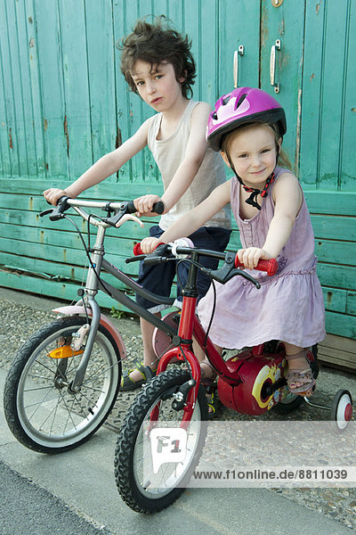 Junge Geschwister sitzen zusammen auf Fahrrädern