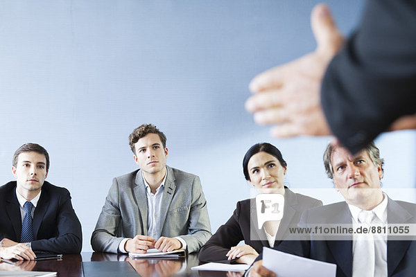 Business associates listen as colleague makes presentation during meeting
