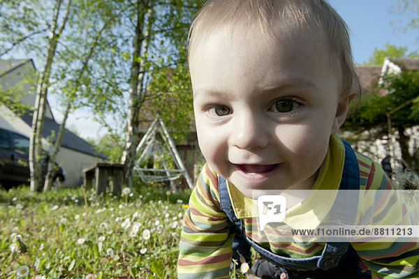 Baby krabbelt im Gras  lächelt fröhlich  Portrait