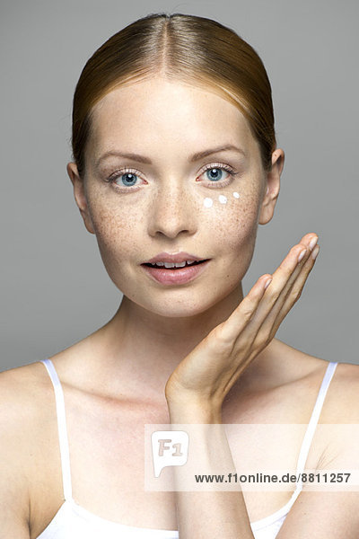 Junge Frau  die Feuchtigkeitscreme auf das Gesicht aufträgt.
