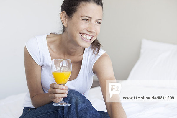 Junge Frau beginnt ihren Tag mit einem Glas Orangensaft