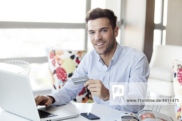 Mann  der sich auf einen Online-Einkauf mit Kreditkarte vorbereitet.