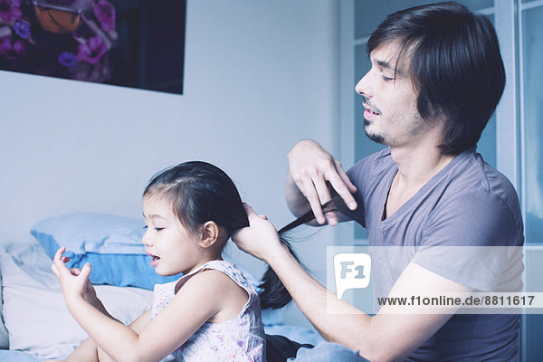 Father putting daughter's hair in ponytail