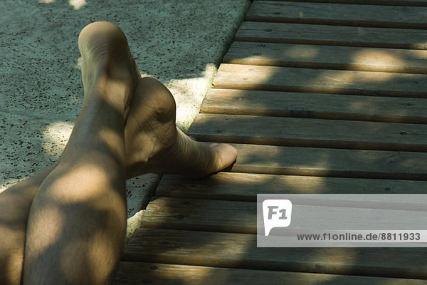 Mann auf Deck liegend  Beine am Knöchel gekreuzt  abgeschnitten