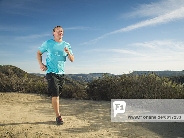 Caucasian man jogging on hilltop