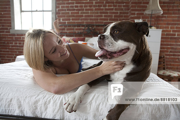 Caucasian woman petting dog on bed