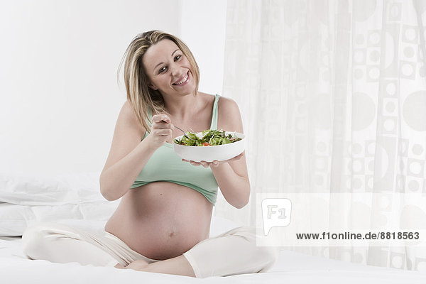 Pregnant Caucasian woman eating salad