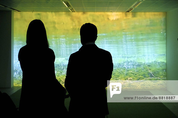Two silhouetted visitors in a gallery looking at a light installation  Frankfurt am Main  Hesse  Germany