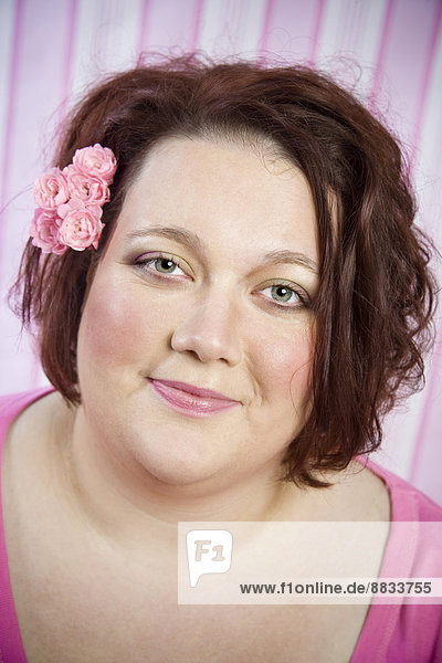 Porträt einer lächelnden Frau mit rosa Blumen