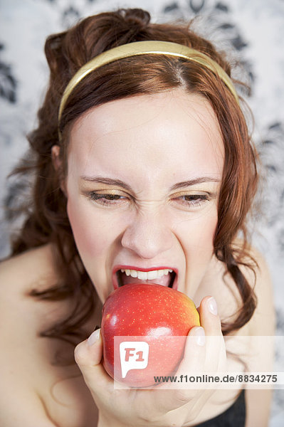 Porträt einer jungen Frau beim Essen von rotem Apfel
