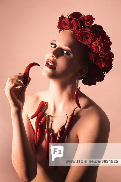 Porträt eines Pin-up-Mädchens mit roten Blumen und roter Paprika verziert