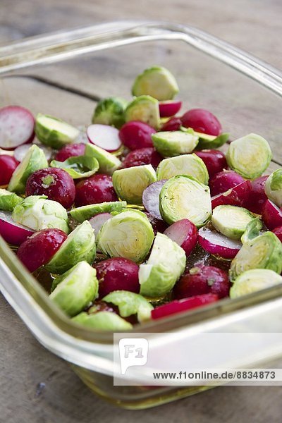 Brussels sprouts and radishes with some oil in a baking dish