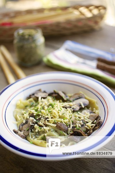 Hausgemachte Grünkohl-Walnusspesto-Ravioli mit Pilzen und veganem Käse und Schnittlauch