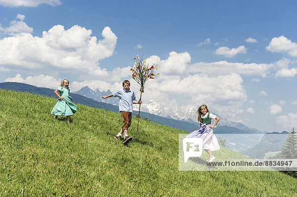 Österreich  Salzburger Land  Altenmarkt-Zauchensee  drei Kinder mit Palmbusch auf Alpweide