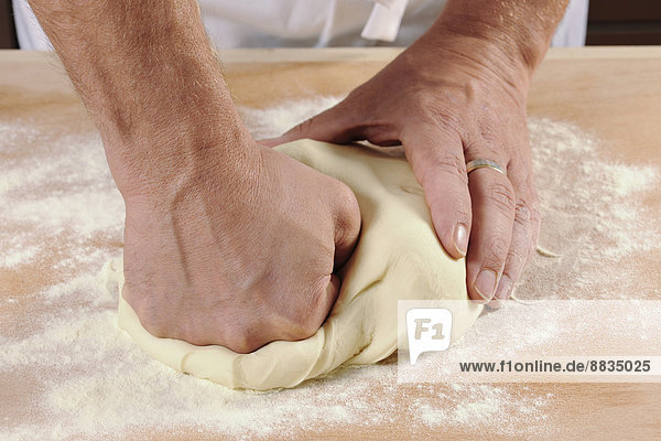 Hände eines Mannes beim Kneten von Nudelteig für hausgemachte Tortelloni