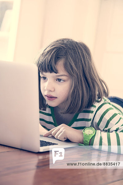 Portrait of little girl using laptop at home
