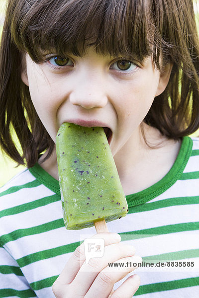 Porträt eines Mädchens mit Kiwi-Eis-Lolly