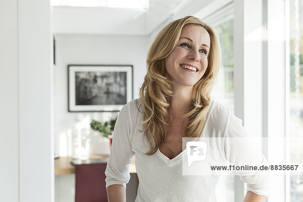Porträt einer glücklichen Frau  die in ihrem hellen  modernen Haus steht.