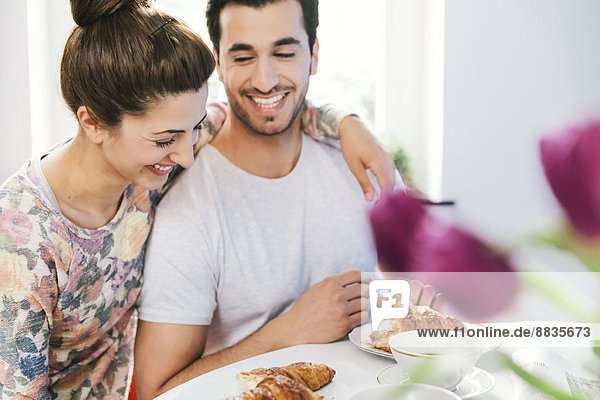 Laughing young couple at breakfast table