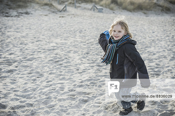 Deutschland  Mecklenburg-Vorpommern  Rügen  lächelnder kleiner Junge  der im Winter am Strand rennt.