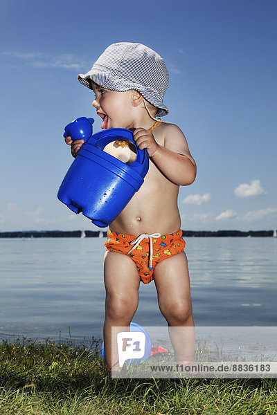 Junge mit Gießkanne vor dem See