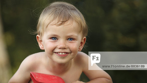 Porträt eines lächelnden kleinen Jungen beim Spielen mit der Schaufel