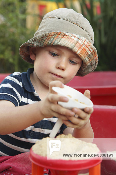 Porträt eines kleinen Jungen  der im Sandkasten spielt