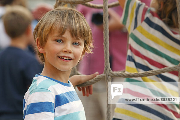 Portrait of smiling little boy in front of climbing net