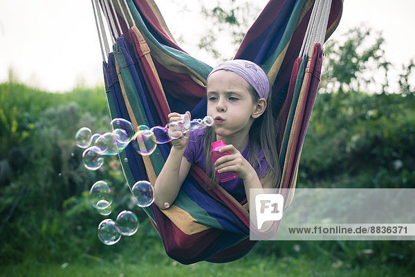 Portrait eines kleinen Mädchens,  das Seifenblasen bläst.
