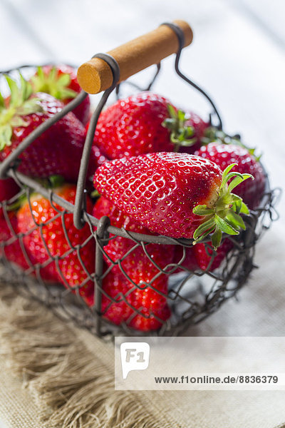 Drahtkorb mit Erdbeeren auf Tuch