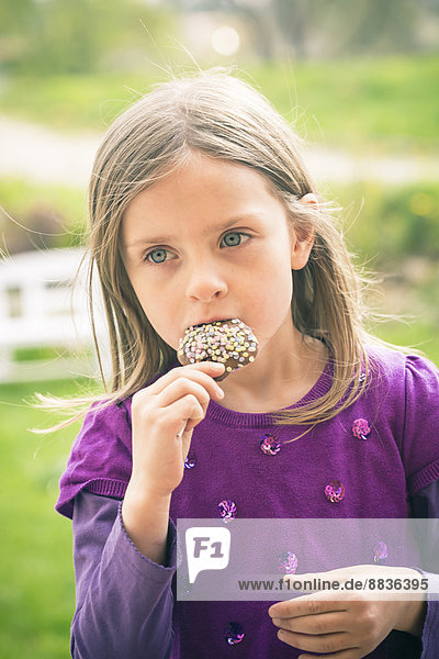 Porträt des kleinen Mädchens  das den Kuchen-Pop testet.