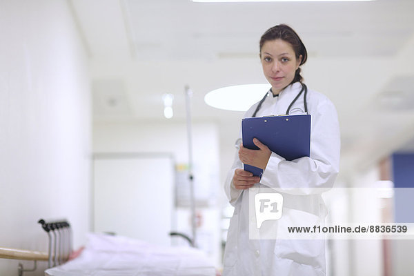 Portrait of young female doctor in hospital holding clip board