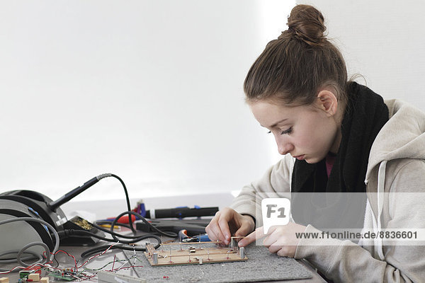 Junge Frau bei der Arbeit am optischen Sensor in einer Elektronikwerkstatt
