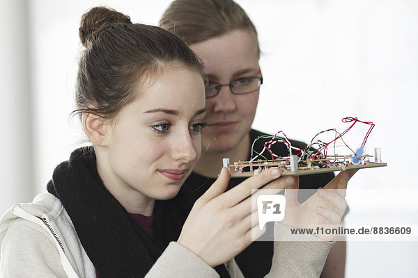 Zwei junge Frauen halten einen optischen Sensor in einer Elektronikwerkstatt.