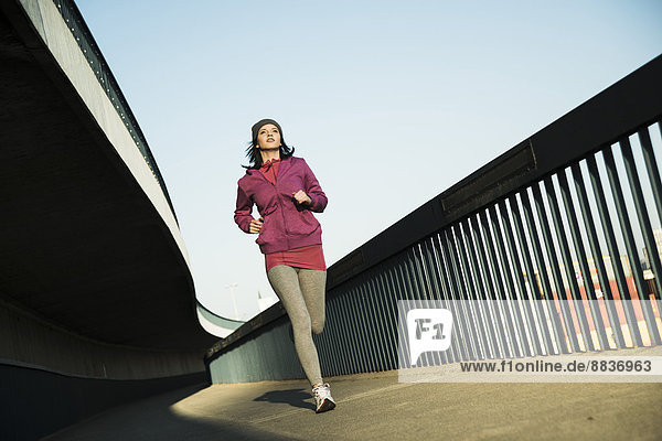 Young female jogger on the move on a bridge