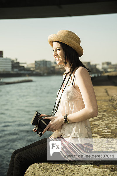 Portrait of young woman with old camera wearing summer hat
