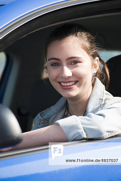 Smiling teenage girl sitting in car  partial view