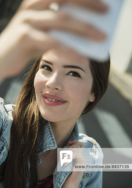 Brunette young woman taking a selfie outdoors
