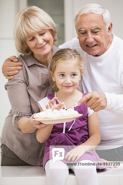 Portrait eines älteren Ehepaares mit Enkelin in der Küche