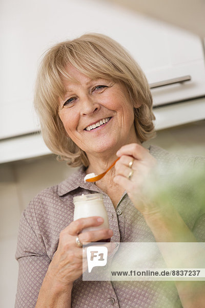 Porträt einer älteren Frau mit Joghurtglas