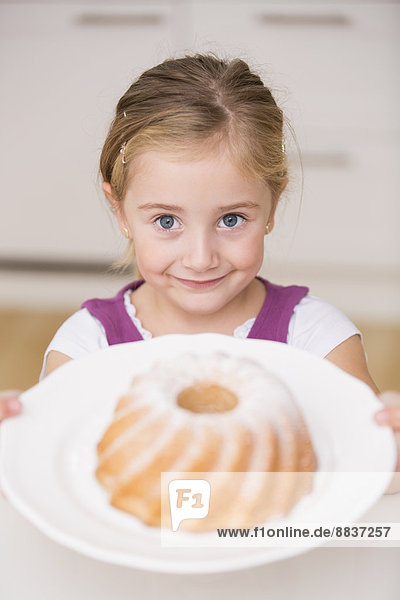 Porträt des lächelnden Mädchens mit Teller mit Ringkuchen
