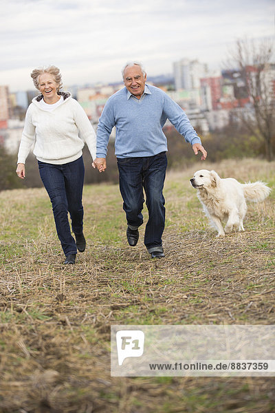 Lächelndes Seniorenpaar läuft Hand in Hand