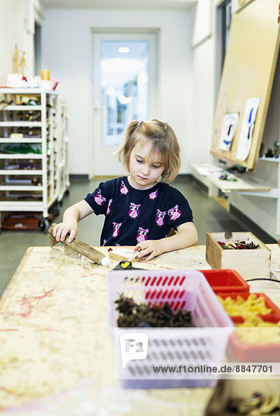 Mädchen machen Kunstprodukt am Tisch im Kindergarten