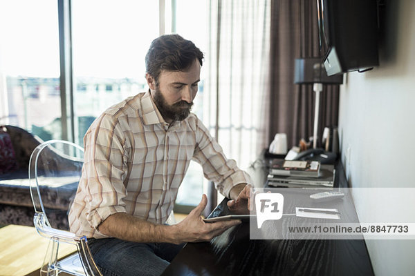 Geschäftsmann berührt digitales Tablett im Hotelzimmer