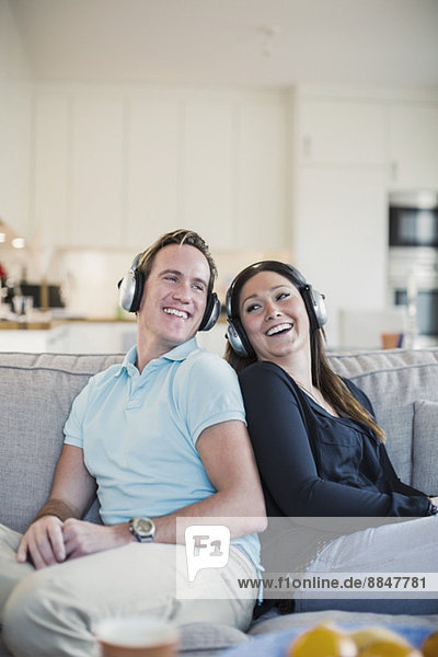 Glückliches Paar beim Musikhören auf dem Sofa zu Hause