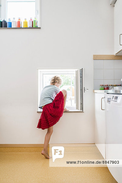 Mädchen geht durch das Küchenfenster hinaus