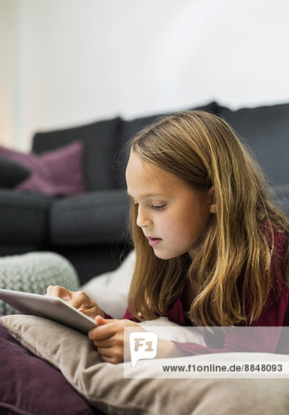 Mädchen mit digitalem Tablett im Wohnzimmer