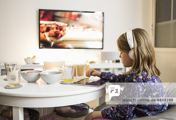 Seitenansicht des Mädchens mit digitalem Tablett am Couchtisch im Wohnzimmer