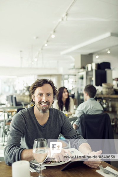Portrait eines reifen Geschäftsmannes mit digitalem Tablett im Restaurant