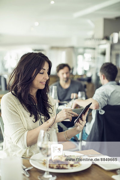 Geschäftsfrau mit Handy und digitalem Tablett im Restaurant